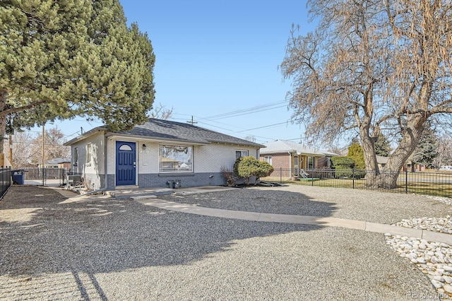 view of front of house with brick siding, fence private yard, gravel driveway, and a gate