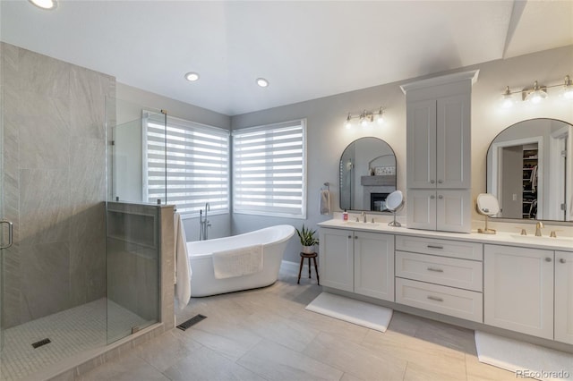 full bathroom with a shower stall, double vanity, a freestanding bath, recessed lighting, and tile patterned floors