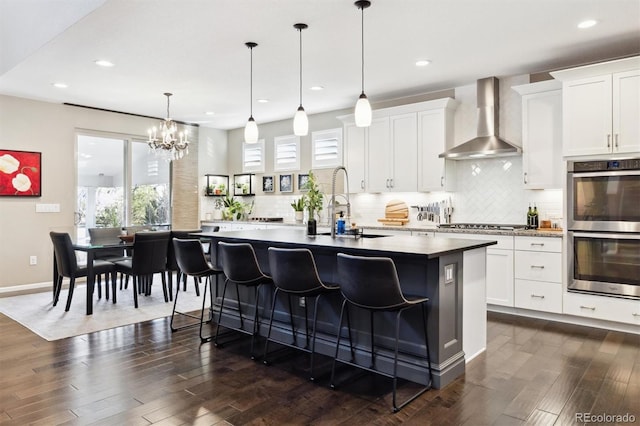 kitchen featuring white cabinetry, wall chimney range hood, and stainless steel appliances