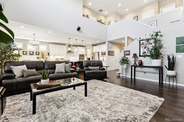 living room featuring a towering ceiling, dark hardwood / wood-style floors, and a notable chandelier