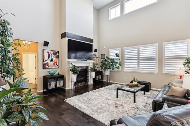 living room with dark hardwood / wood-style flooring, a towering ceiling, and a notable chandelier