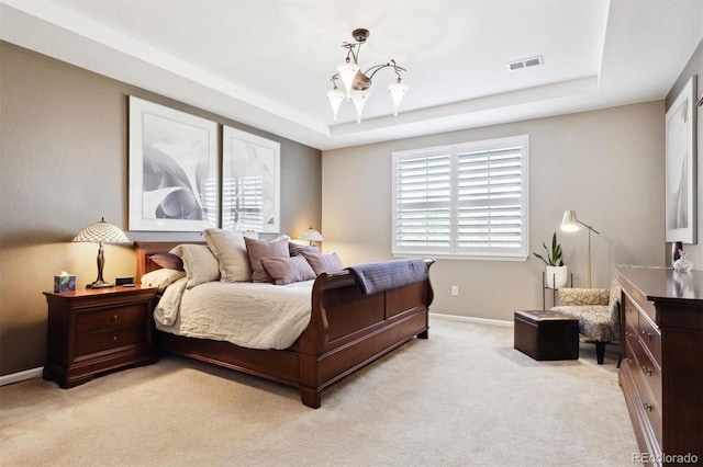 carpeted bedroom featuring an inviting chandelier and a tray ceiling