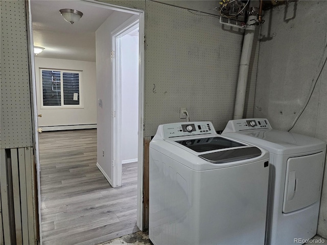 clothes washing area featuring washer and clothes dryer, light hardwood / wood-style floors, and a baseboard heating unit