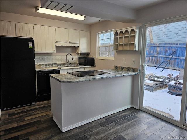 kitchen with sink, kitchen peninsula, dark hardwood / wood-style flooring, and black appliances