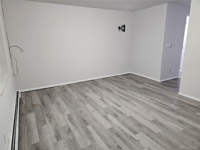 spare room featuring a baseboard radiator and light wood-type flooring