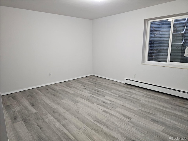 spare room featuring a baseboard radiator and light wood-type flooring