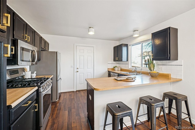 kitchen featuring stainless steel appliances, sink, a kitchen bar, tasteful backsplash, and kitchen peninsula