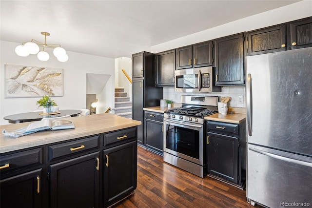 kitchen with dark hardwood / wood-style flooring, stainless steel appliances, pendant lighting, and tasteful backsplash