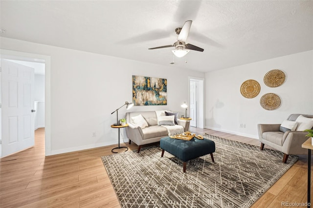 living room with a textured ceiling, ceiling fan, and wood-type flooring