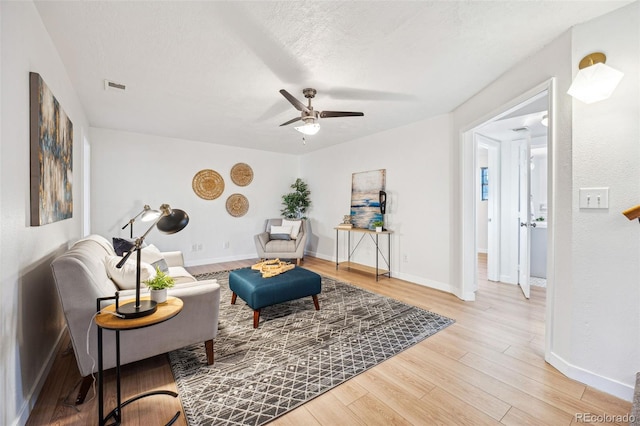 living area with a textured ceiling, ceiling fan, and wood-type flooring