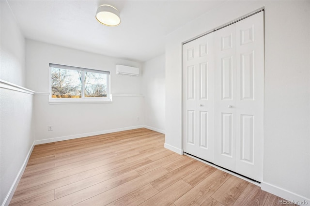 unfurnished bedroom featuring a wall unit AC, a closet, and light hardwood / wood-style floors