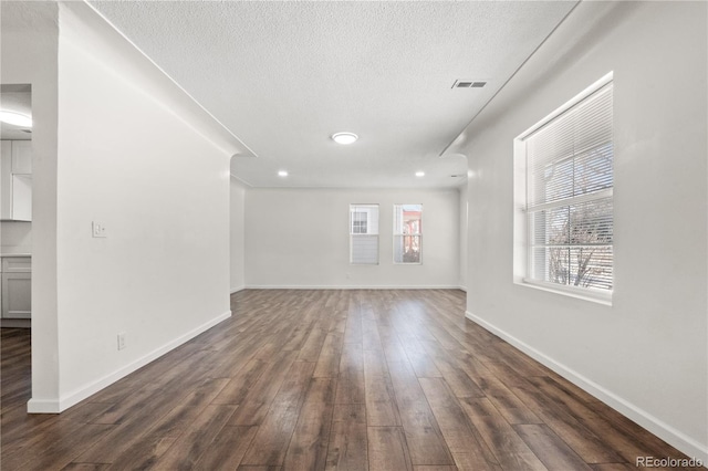 unfurnished living room featuring a textured ceiling and dark wood-type flooring