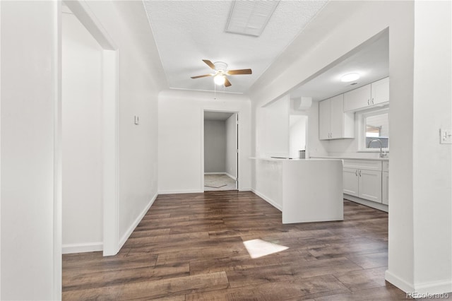 interior space with ceiling fan, white cabinets, dark wood-type flooring, and a textured ceiling