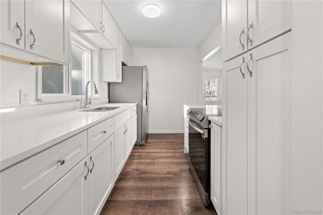 kitchen with appliances with stainless steel finishes, dark hardwood / wood-style flooring, white cabinetry, and sink