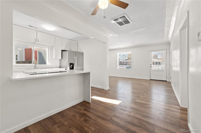 kitchen with white cabinetry, kitchen peninsula, stainless steel refrigerator with ice dispenser, dark hardwood / wood-style flooring, and a textured ceiling