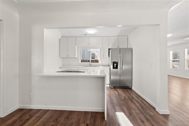 kitchen featuring white cabinetry, sink, stainless steel fridge, dark hardwood / wood-style floors, and kitchen peninsula