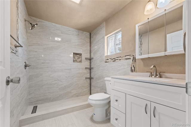 bathroom featuring tiled shower, vanity, and toilet