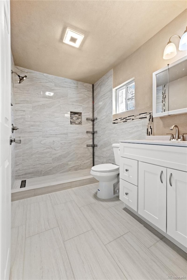 bathroom featuring toilet, vanity, and tiled shower