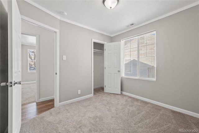 unfurnished bedroom featuring carpet floors, a closet, crown molding, and a textured ceiling