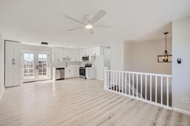 unfurnished living room with sink, french doors, ceiling fan, and light wood-type flooring