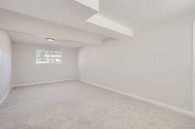 carpeted empty room with beamed ceiling and a textured ceiling