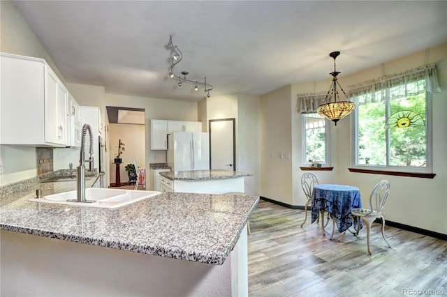 1313 Iris Cir, Broomfield, CO 80020 - kitchen with freestanding refrigerator, a peninsula, light wood finished floors, light stone countertops, and white cabinetry