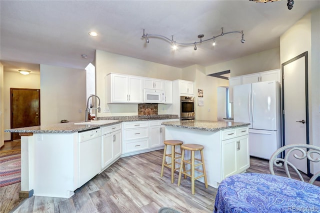 1313 Iris Cir, Broomfield, CO 80020 - kitchen with white appliances, a peninsula, white cabinets, light stone countertops, and recessed lighting
