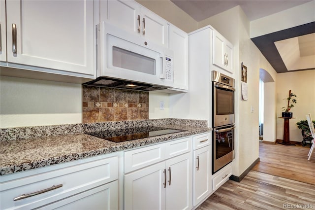 1313 Iris Cir, Broomfield, CO 80020 - kitchen featuring white microwave, stainless steel double oven, backsplash, light wood-style flooring, and stone counters