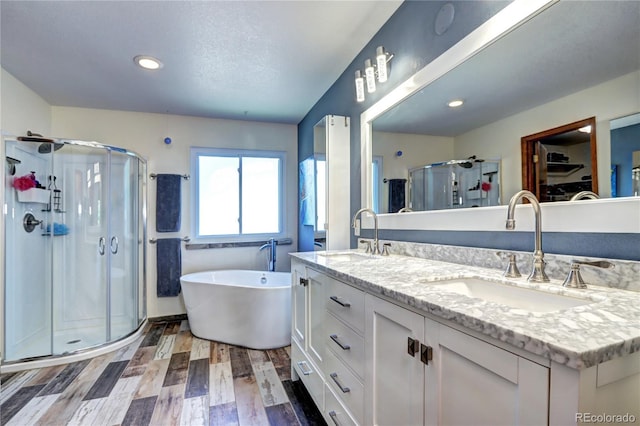 1313 Iris Cir, Broomfield, CO 80020 - bathroom featuring a shower stall, double vanity, a spacious closet, wood finished floors, and a soaking tub