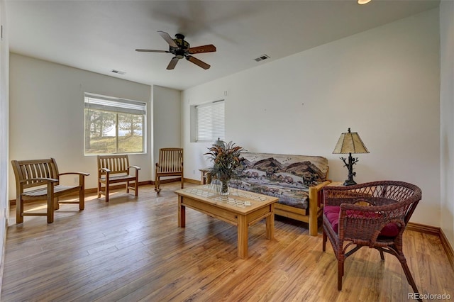 living area featuring light wood finished floors, ceiling fan, baseboards, and visible vents