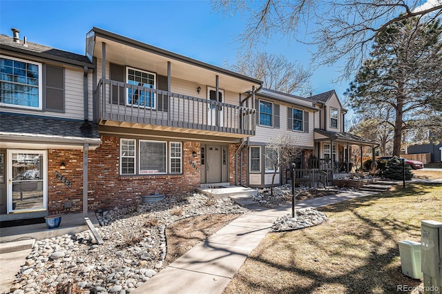 view of property with a balcony and brick siding