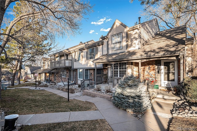 view of front of home with a residential view, brick siding, a balcony, and a front lawn