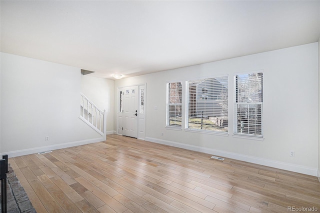 interior space with baseboards, stairway, visible vents, and light wood-style floors