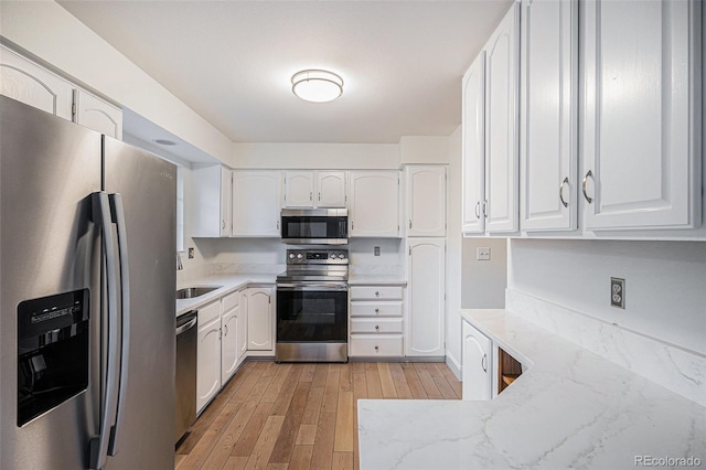 kitchen featuring light wood-type flooring, white cabinetry, stainless steel appliances, and light stone counters