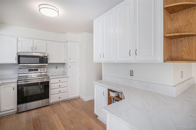 kitchen featuring light stone counters, light wood-style flooring, white cabinetry, appliances with stainless steel finishes, and open shelves