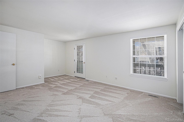 unfurnished room featuring baseboards, visible vents, and light colored carpet