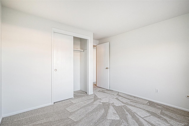 unfurnished bedroom featuring baseboards, a closet, and light colored carpet