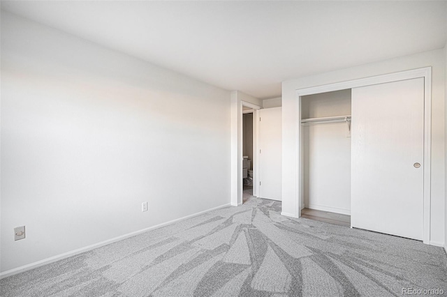 unfurnished bedroom with carpet floors, baseboards, and a closet