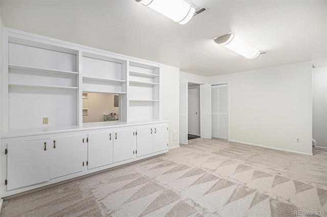 empty room featuring light carpet, visible vents, and baseboards