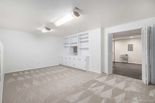 empty room featuring electric panel, light colored carpet, visible vents, and baseboards