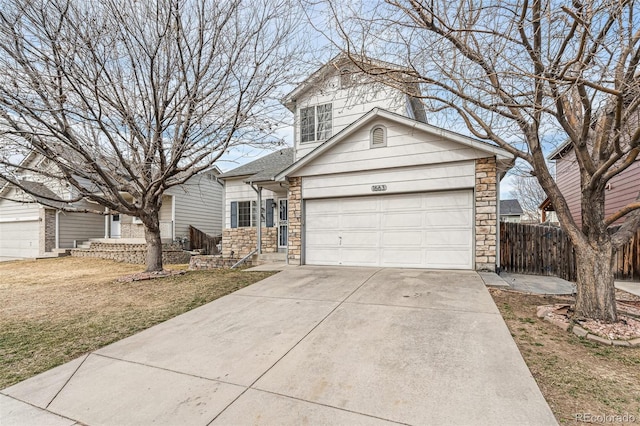 traditional-style home with driveway, a shingled roof, stone siding, an attached garage, and fence