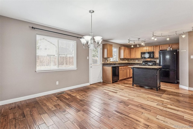 kitchen with black appliances, tasteful backsplash, and light wood-style flooring