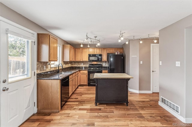 kitchen with black appliances, visible vents, backsplash, and a sink