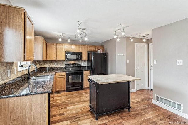 kitchen with light wood-style flooring, a sink, visible vents, decorative backsplash, and black appliances