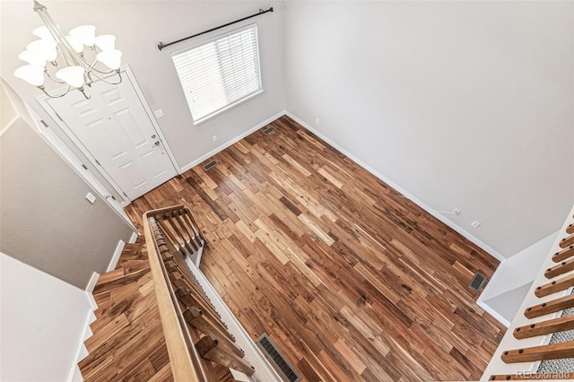 foyer entrance featuring an inviting chandelier, baseboards, and wood finished floors