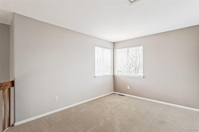 carpeted spare room with visible vents and baseboards