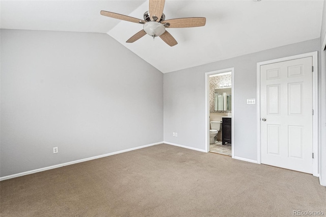 unfurnished bedroom with carpet, vaulted ceiling, ceiling fan, ensuite bath, and baseboards