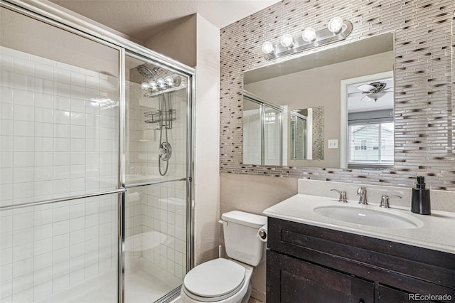 full bathroom featuring a stall shower, ceiling fan, vanity, and toilet