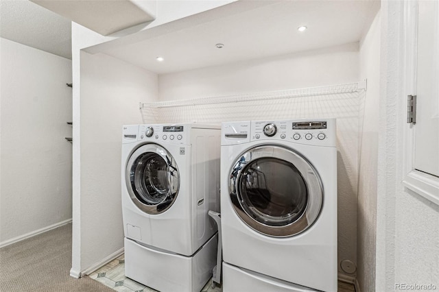 clothes washing area featuring washing machine and dryer, light colored carpet, and baseboards