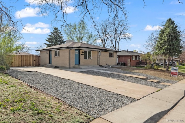 view of front of home with brick siding, fence, and entry steps